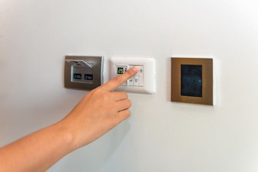 Image of someone pressing a control panel attached to an hvac unit. Heat Pump Versus Furnace.