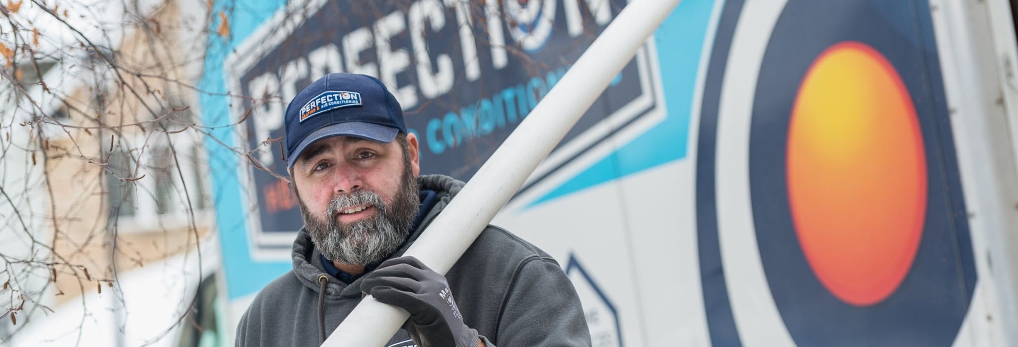 Perfection Heating and Air Conditioning technician in front of service van.