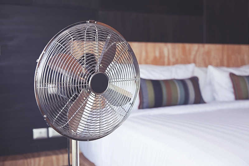 Old electric fan near the bed in the room improving indoor air quality